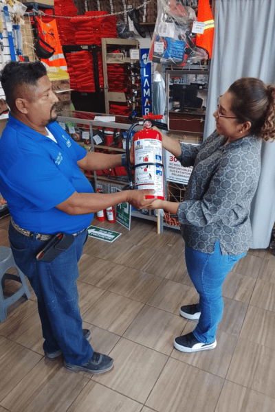 Técnico LAMAR entregando extintor certificado a cliente en sucursal